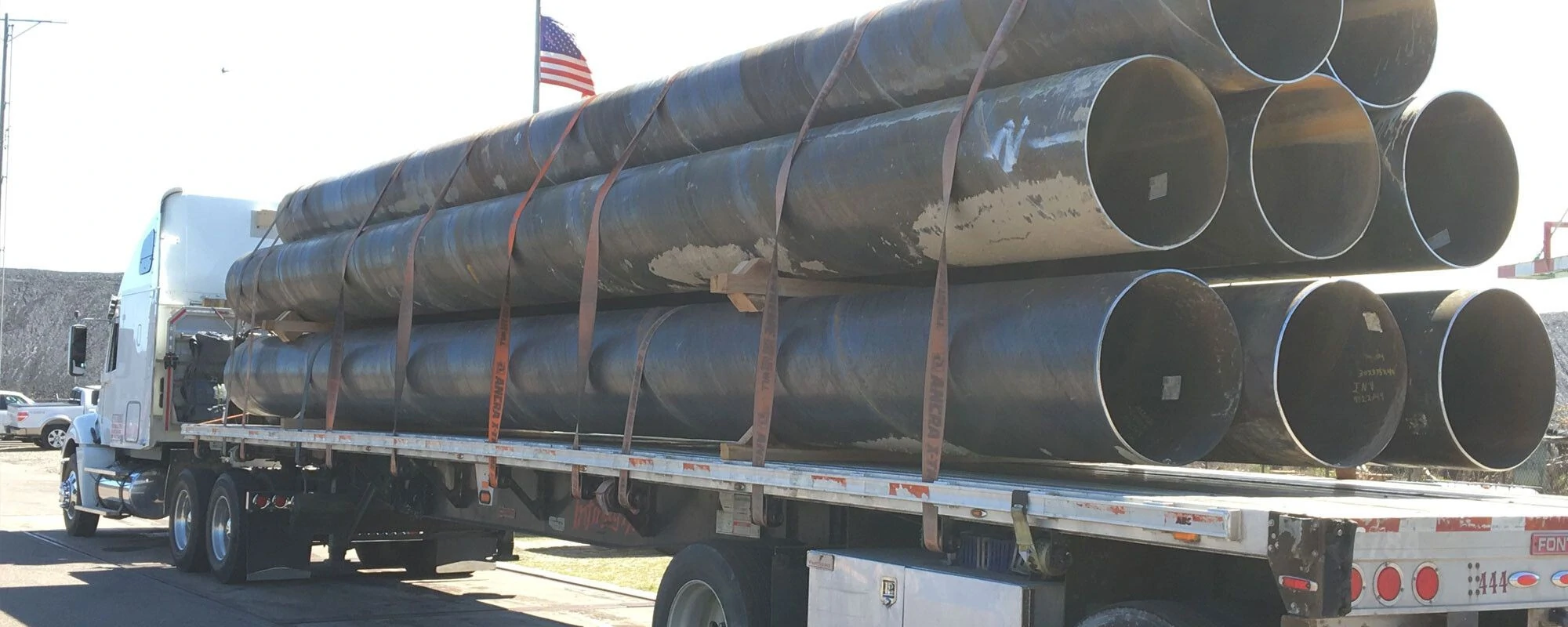 A truck loaded with large metal pipes